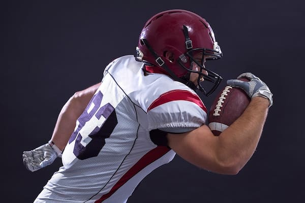 Football player running with the football in his hand. Dr. Ethan Bregman offers specialized counseling for athletes.