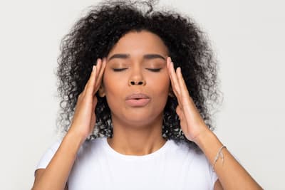 attractive young woman of color touching her temples trying to alleviate stress.